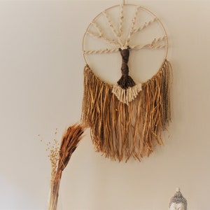 May include: A macrame wall hanging with a circular wooden frame and a tree design. The hanging has brown and white tassels.