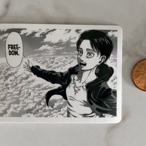 May include: A rectangular sticker featuring a black and white manga illustration of a character with outstretched arms, set against a cloudy sky. The word "FREEDOM" is in a speech bubble. A penny is next to the sticker.
