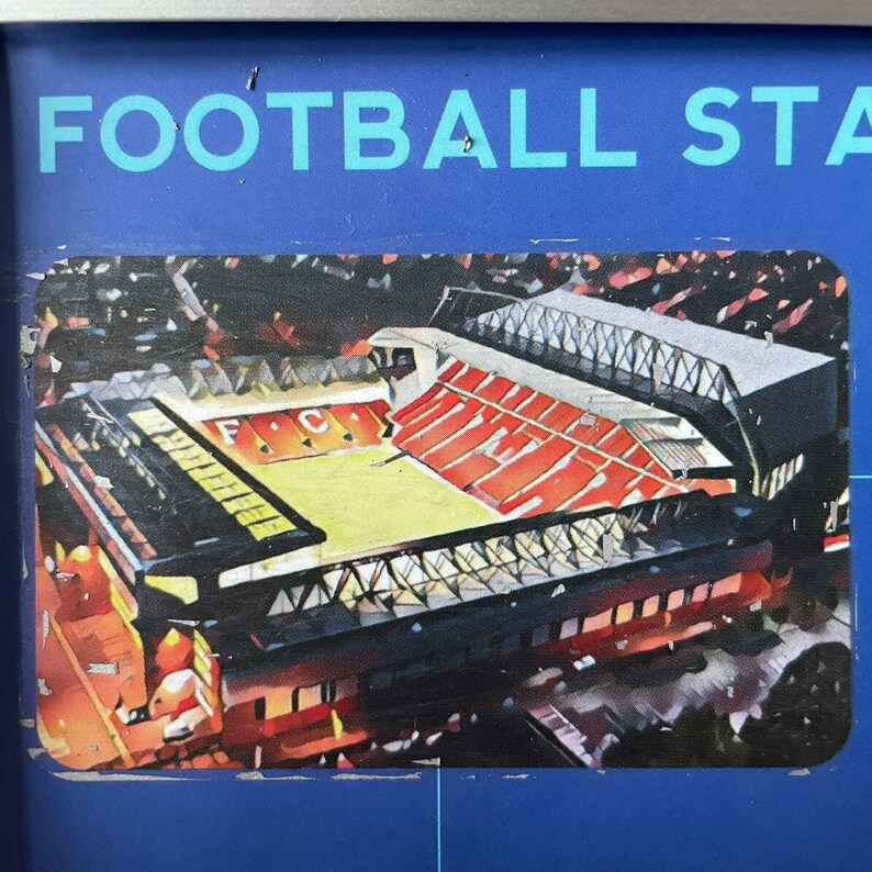 Peut inclure: Vue a&eacute;rienne d'un grand stade de football rouge et noir avec un terrain vert. Le stade est entour&eacute; d'une grande foule de personnes. Le stade a un grand tableau d'affichage avec les lettres "F.C." dessus.