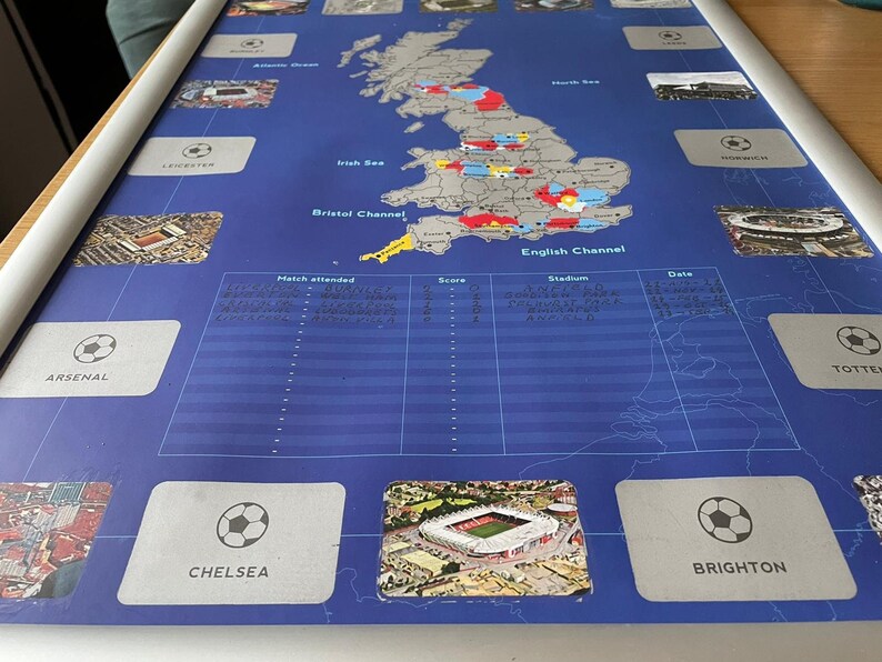 Peut inclure: Une carte bleue et blanche du Royaume-Uni avec une liste des &eacute;quipes de Premier League et leurs stades. La carte montre l'emplacement du stade de chaque &eacute;quipe. La liste comprend le nom de l'&eacute;quipe, le nom du stade et la date du match. La carte est sur un fond bleu avec des lignes blanches.