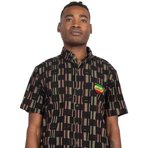 May include: A black and green short-sleeved button-down shirt with a geometric pattern. The shirt has a small round patch with the text "Jah Roots" in yellow.