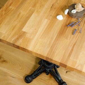 May include: A close-up of a light wood table top with a natural wood grain pattern. The table top is made of multiple pieces of wood that have been joined together. There are a few seashells and a sprig of lavender on the table top.