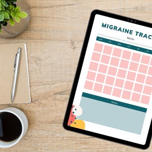 May include: A digital migraine tracker on a tablet with a calendar grid and a notes section. The calendar has pink squares for each day of the month. The notes section is a light blue rectangle with a dark blue border. The tablet is on a wooden surface with a notebook, pen, and a cup of coffee.