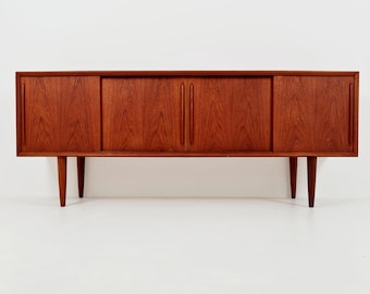 May include: A long, rectangular wooden sideboard featuring a warm, reddish-brown wood grain finish. The piece has four vertical cabinet doors with integrated wooden handles and is supported by four tapered, cylindrical wooden legs.