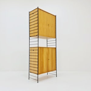 May include: A tall, black metal shelving unit with two wooden cabinets. The cabinets have two doors each and are made of light wood. The shelves are made of metal and are spaced evenly apart.