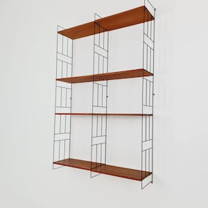 May include: A mid-century modern wall-mounted shelving unit. The unit features four wooden shelves in a warm brown hue, supported by a black metal frame. The frame has a geometric design, creating a stylish storage solution. The shelves are approximately 91 cm wide.
