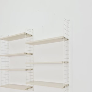 May include: White metal wall-mounted shelving unit with five shelves. The shelves are made of wood and are a light beige colour.