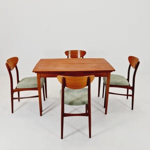 Può includere: Un set da pranzo moderno di metà secolo con un tavolo rettangolare in legno e quattro sedie. Le sedie hanno schienali curvi e sedili imbottiti verde chiaro. Il tavolo e le sedie sono in legno con una calda finitura marrone rossiccio.