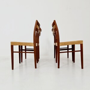 May include: Set of four mid-century modern dining chairs with a light brown woven seat and a dark brown wood frame.