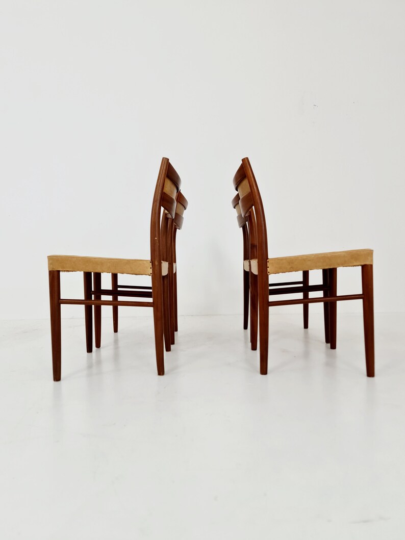 May include: Set of four mid-century modern dining chairs with a light brown woven seat and a dark brown wood frame.