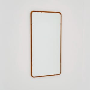 Peut inclure: Miroir rectangulaire avec un cadre en bois brun. Le miroir a des coins arrondis et est monté sur un mur blanc. La couleur du cadre contraste avec le fond blanc, créant un design simple mais élégant.