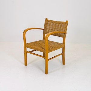 May include: A wooden chair with a woven rope seat and back. The chair has a light brown finish and curved arms.