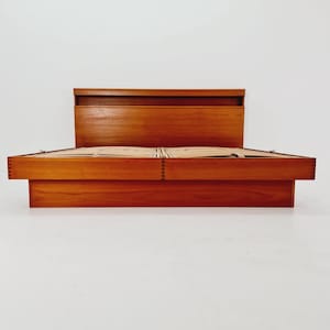 Peut inclure: Un cadre de lit en bois de style moderne du milieu du siècle avec une tête de lit. Le cadre de lit est en bois aux tons chauds et présente un design bas. La tête de lit a une forme rectangulaire avec un dessus encastré.