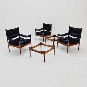 May include: A set of four mid-century modern chairs with black leather upholstery and a wood frame, arranged around a glass-top coffee table with a wood frame.