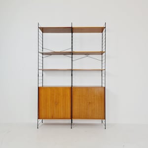 May include: A black metal shelving unit with wooden shelves and two closed cabinets. The unit has a mid-century modern design.