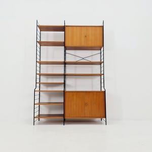 Op de afbeelding: Een boekenrek in mid-century modern stijl met een zwart metalen frame en houten planken en kasten. De unit heeft meerdere planken en twee kasten met houten deuren. Het ontwerp is minimalistisch en functioneel.