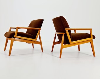 May include: Two brown velvet armchairs with wooden frames. The chairs have a mid-century modern design with angled legs and arms.