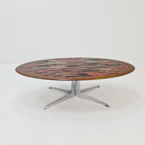 Peut inclure: Une table basse ronde de style moderne du milieu du siècle avec un plateau en mosaïque de carreaux dans des tons de rouge, noir et vert. La table a un piétement chromé à quatre pieds.