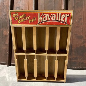 May include: A wooden shoe polish display stand with the text "Die Schuh polier mit Kavalier" in red and white lettering.