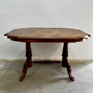 Könnte beinhalten: Ein antiker Beistelltisch aus dunklem Holz mit ovaler Platte und verzierten, geschnitzten Beinen. Der Tisch hat eine satte, rotbraune Oberfläche und dekorative Details an den Beinen und am Zargen. Der Tisch ist ca. 76 cm lang.
