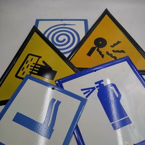 Könnte beinhalten: Fünf vintage Metallschildchen mit blauen und gelben Rändern und weißen Hintergründen. Die Schilder zeigen verschiedene Brandschutzsymbole, darunter einen Feuerlöscher, einen Schlauch, eine Hand, die einen Feueralarm hält, einen Feueralarm und einen Feuerwehrschlauch.