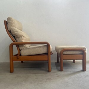 May include: A vintage lounge chair and footstool set. The chair features a wooden frame with a curved back and armrests. The cushions are upholstered in a light beige fabric. The footstool has a matching wooden frame and upholstered top.