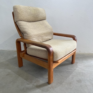 May include: A vintage armchair featuring a light beige fabric seat and backrest. The wooden frame has a warm, natural finish. The chair has a high back and armrests, offering a comfortable seating experience. The chair's dimensions are approximately 80 cm in height.