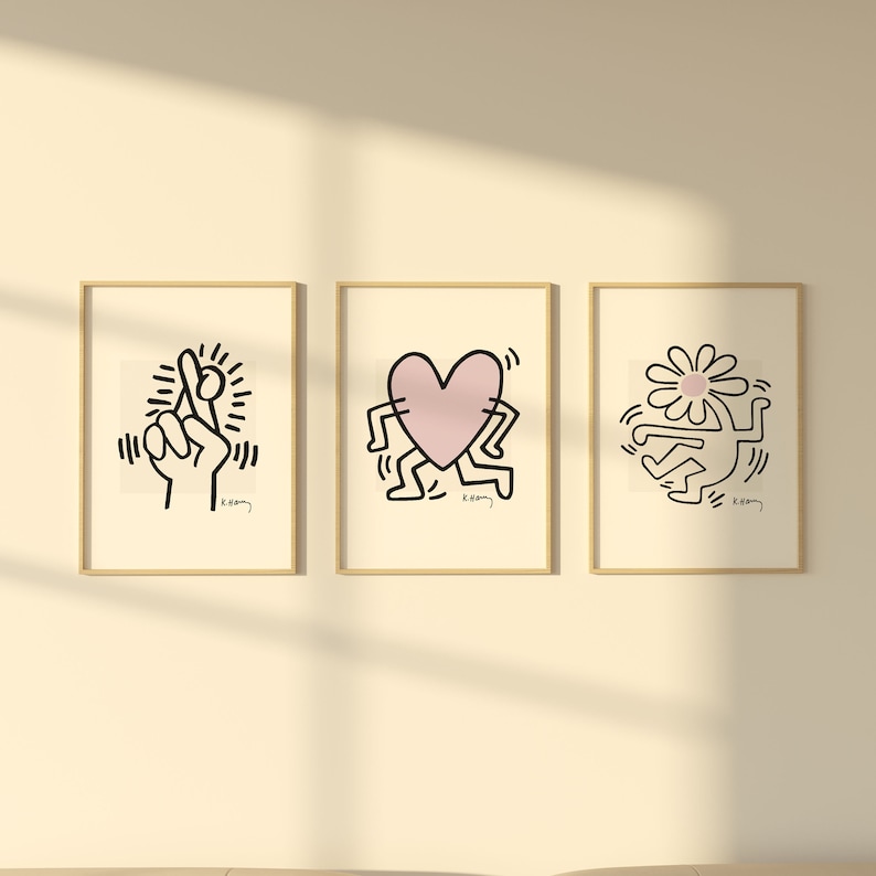 May include: Three framed black and white illustrations with pink accents. The illustrations are of a hand making a pinky promise, a heart with legs, and a figure with a flower on its head. Each illustration is signed "K. Haring".