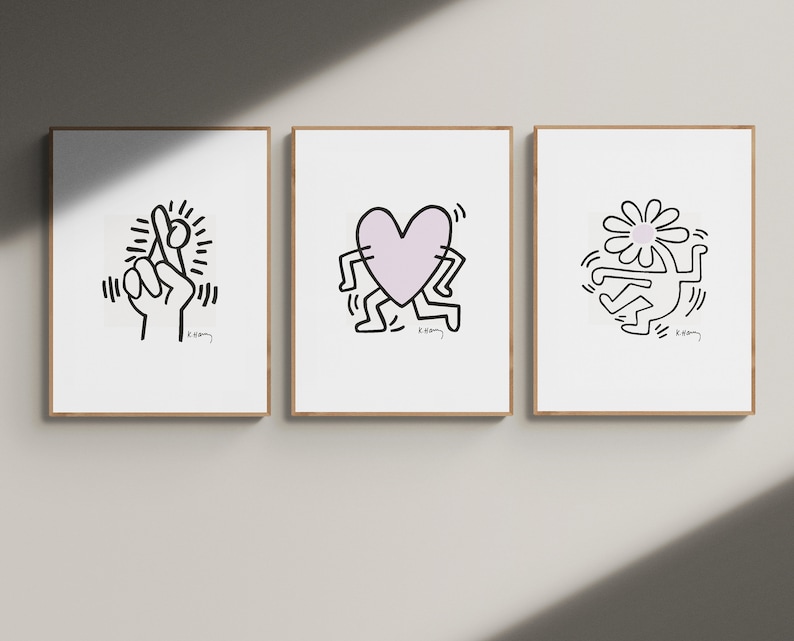 May include: Three framed prints with black and white line drawings by Keith Haring. The first print features a hand with crossed fingers, the second print features a heart with legs, and the third print features a flower with a person inside.