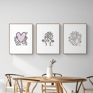 May include: Three framed black and white illustrations with pink accents. The illustrations are of a heart, a hand with crossed fingers, and a flower. Each illustration is surrounded by a thin black outline and has the word "K.O.O.M" written in the bottom right corner.