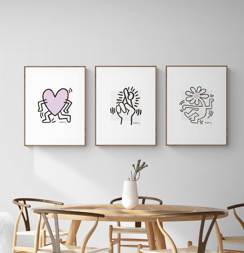 May include: Three framed black and white illustrations with pink accents. The illustrations are of a heart, a hand with crossed fingers, and a flower. Each illustration is surrounded by a thin black outline and has the word "K.O.O.M" written in the bottom right corner.