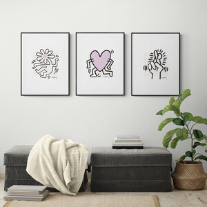 May include: Three framed black and white prints of artwork by Keith Haring. The prints feature a flower, a heart, and a hand. Each print has the artist's signature and the word "K. Haring" in the bottom right corner.