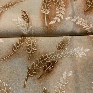 May include: Close-up of fabric featuring a repeating pattern of stylized leaves and branches in shades of brown and cream. The leaves have a detailed design, and the background has a subtle, mottled effect.