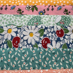 Op de afbeelding: Een close-up van stoffen stroken met verschillende patronen. De stoffen omvatten een perzikstrip met kinderen, een gele strip met witte stippen en een roze strip met bloemen- en vlindermotieven. Andere stroken hebben madeliefjes-, blad- en bloempatronen.