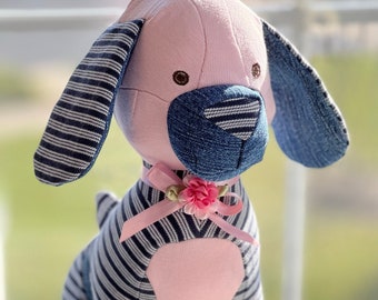 May include: A pink and blue striped handmade stuffed dog toy with a pink bow and flower accent. The dog has a blue denim nose and ears.