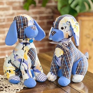May include: Two blue and white patchwork fabric dog plushies with black eyes and blue noses. The plushies are sitting on a wooden table.