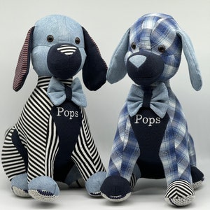 May include: Two blue and white striped fabric dog plushes with black bow ties. The plushes are sitting on a white surface. The plushes have the name "Pops" embroidered on their chests.
