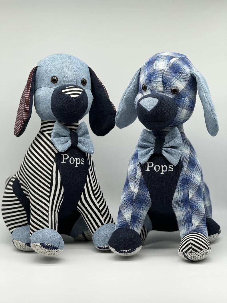 May include: Two blue and white striped fabric dog plushes with black bow ties. The plushes are sitting on a white surface. The plushes have the name "Pops" embroidered on their chests.