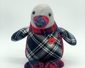May include: A stuffed penguin toy with a gray head and a red, black, and white plaid body. The penguin has a red heart-shaped button on its chest and black eyes. The penguin is sitting upright.