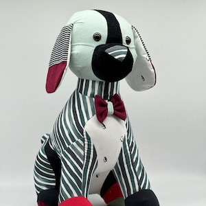 May include: A plush toy dog with a striped green and white body, black and white ears, a black nose, and a red bow tie.