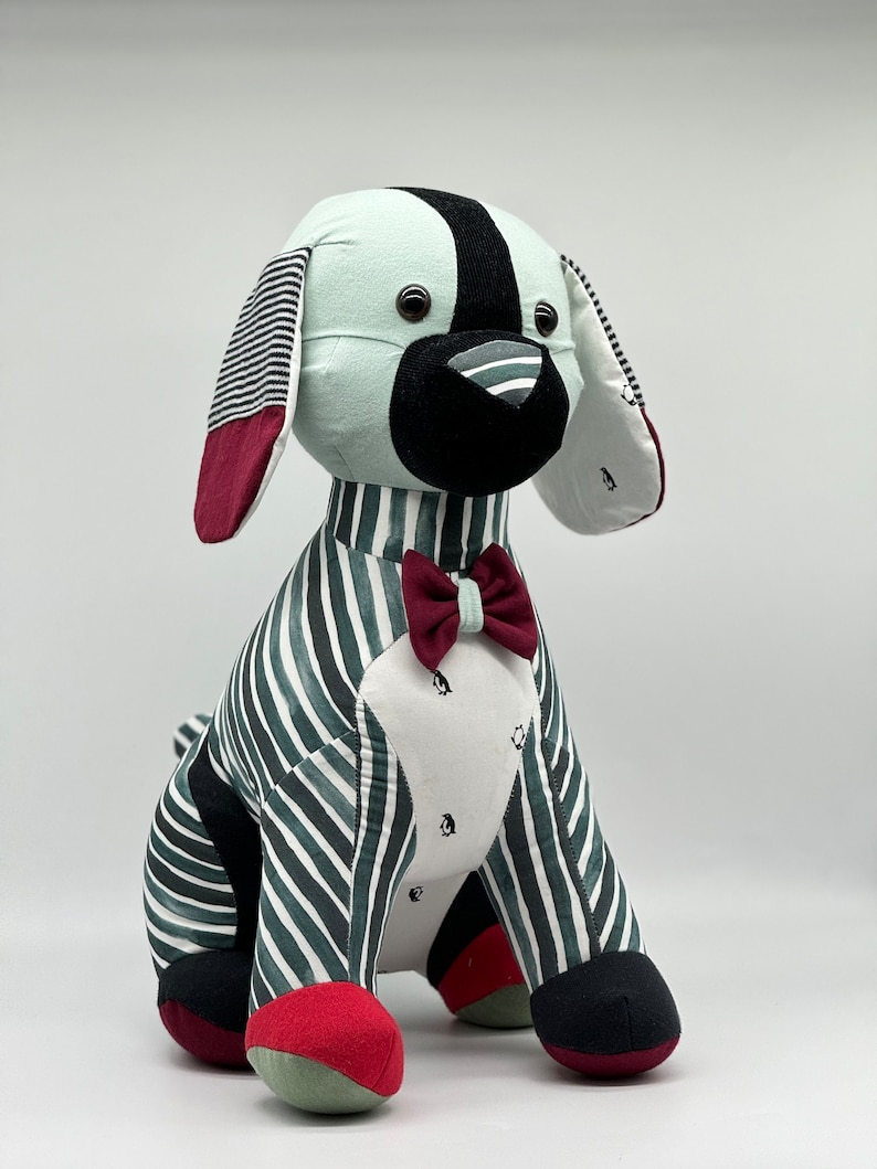 May include: A plush toy dog with a striped green and white body, black and white ears, a black nose, and a red bow tie.
