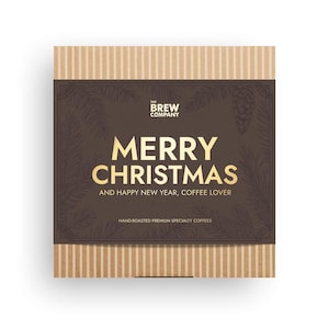 May include: A rectangular gift box with a brown background and gold text that reads "MERRY CHRISTMAS AND HAPPY NEW YEAR, COFFEE LOVER." The box has a striped beige border and the words "THE BREW COMPANY" at the top.
