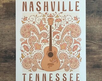 May include: A vintage-style poster featuring a brown guitar surrounded by pink and brown paisley floral designs. The text "NASHVILLE TENNESSEE" is printed in brown at the top and bottom of the poster.