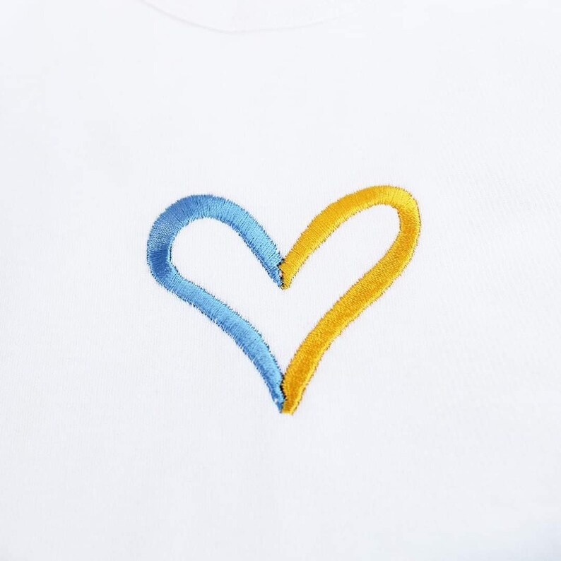 May include: A white t-shirt with a blue and yellow embroidered heart.