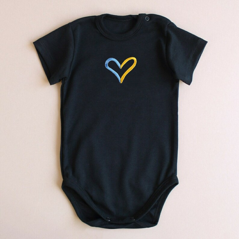 May include: A black short-sleeved bodysuit with a yellow and blue heart embroidered on the front.