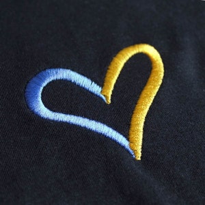 May include: A blue and yellow embroidered heart on a black fabric background.