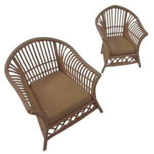 May include: Two miniature armchairs featuring a light brown, woven-style texture. Each chair has a high, rounded backrest with vertical slats, a flat seat, and a decorative lattice pattern along the base, all rendered in a uniform light brown color.