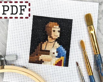 May include: A completed cross-stitch project featuring a portrait of a person with brown hair and a blue garment, set against a black background. The word "PDF" is in the upper left corner. Paintbrushes and a wooden embroidery hoop are in the background.