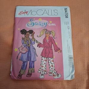May include: A pink and white McCall's sewing pattern envelope featuring illustrations of two girls in pajamas. The text on the envelope reads "Easy McCall's" and "Sassy Girl". The pattern number is M4708.