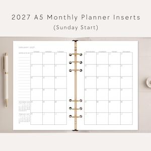 May include: A beige A5 ring binder containing 2027 monthly planner inserts with a Sunday start. The open planner displays a January 2027 calendar grid, a notes and to-do section, and small reference calendars for December 2026 and February 2027.